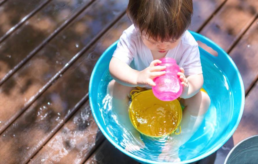 小孩在儿童泳池里用粉色吸管杯喝水